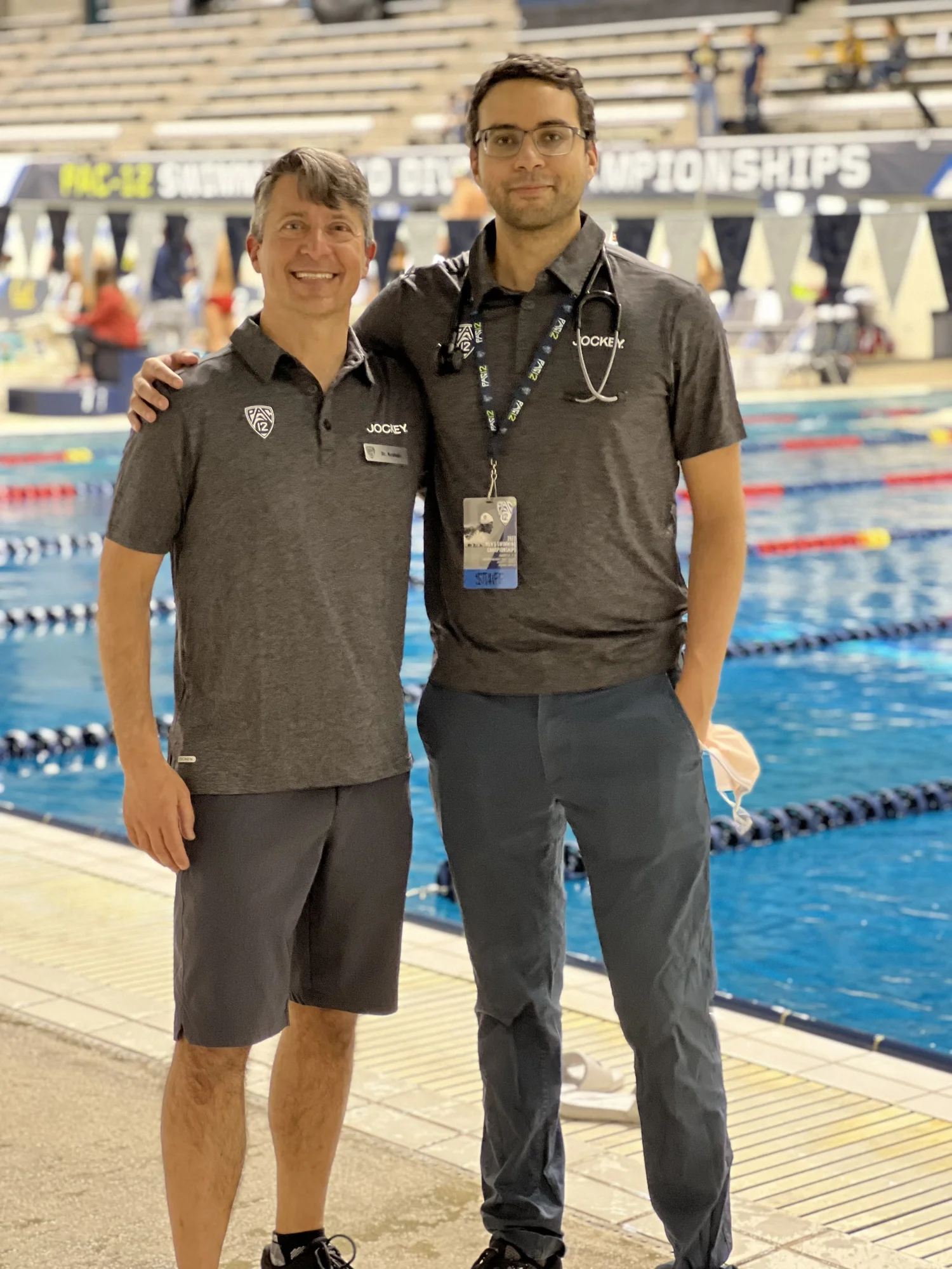 Dr. Ahmed El-Sayed and Dr. Brian Krabak standing poolside at a swimming championship